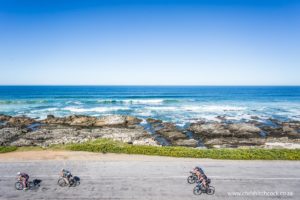 40km before the start/finish line riders battle into the head wind, known locally as the ‘Beasterly Easterly’. I climbed up the dunes next to the road to get a more panoramic view of the riders and surf using a wide angle lens.